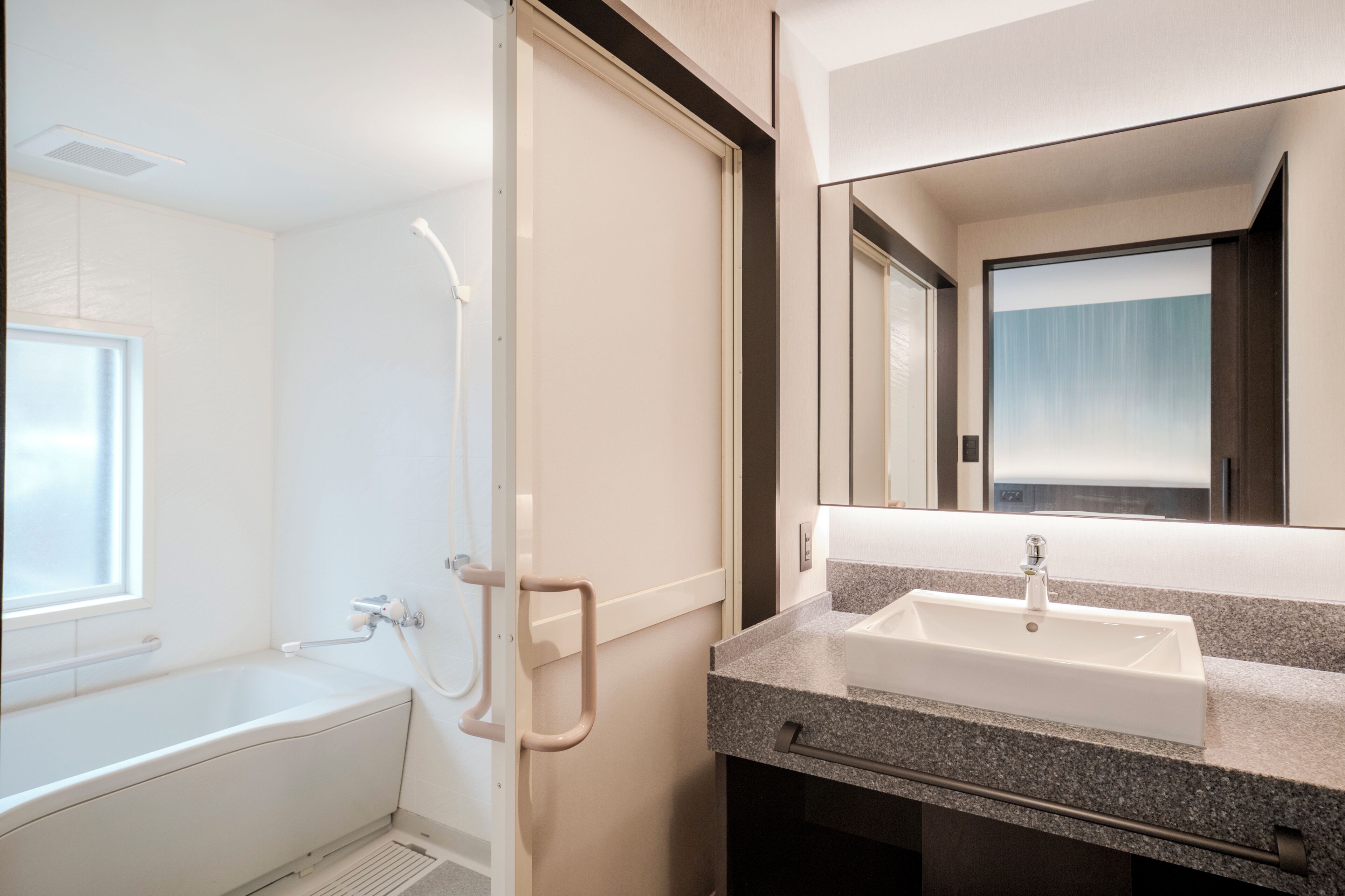A modern bathroom with a bathtub, a sink, and a mirror.