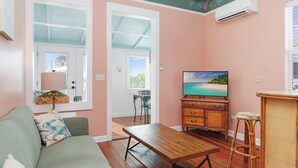 Una sala acogedora con un sofá, una mesa de madera, un televisor y una ventana con persianas.