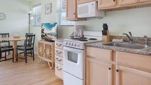 Una cocina con armarios de madera, estufa, microondas, fregadero y un comedor con mesa y sillas.