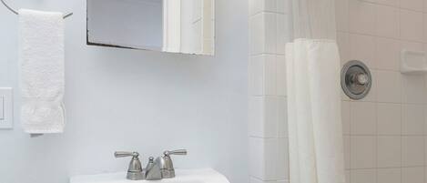 A bathroom with a white sink, a mirror, and a shower with a curtain.