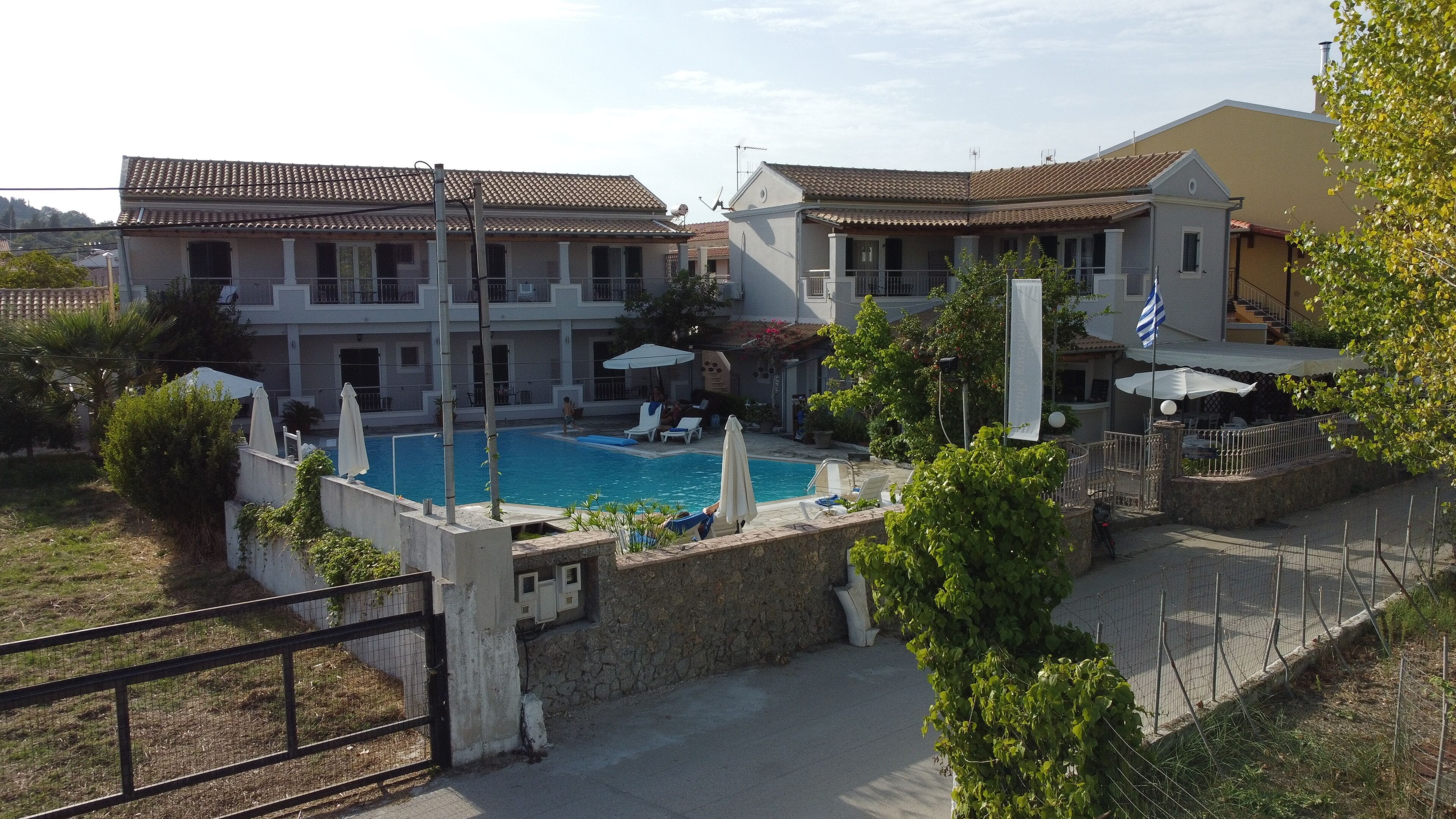 A residential area with a swimming pool surrounded by houses, a gate, and a fence.