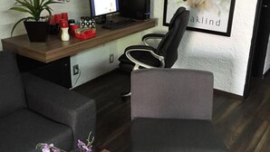 A modern office space with a desk, computer, and two chairs. There are framed pictures on the wall and a poster with flowers. - Aurora Suites (Guadalajara)