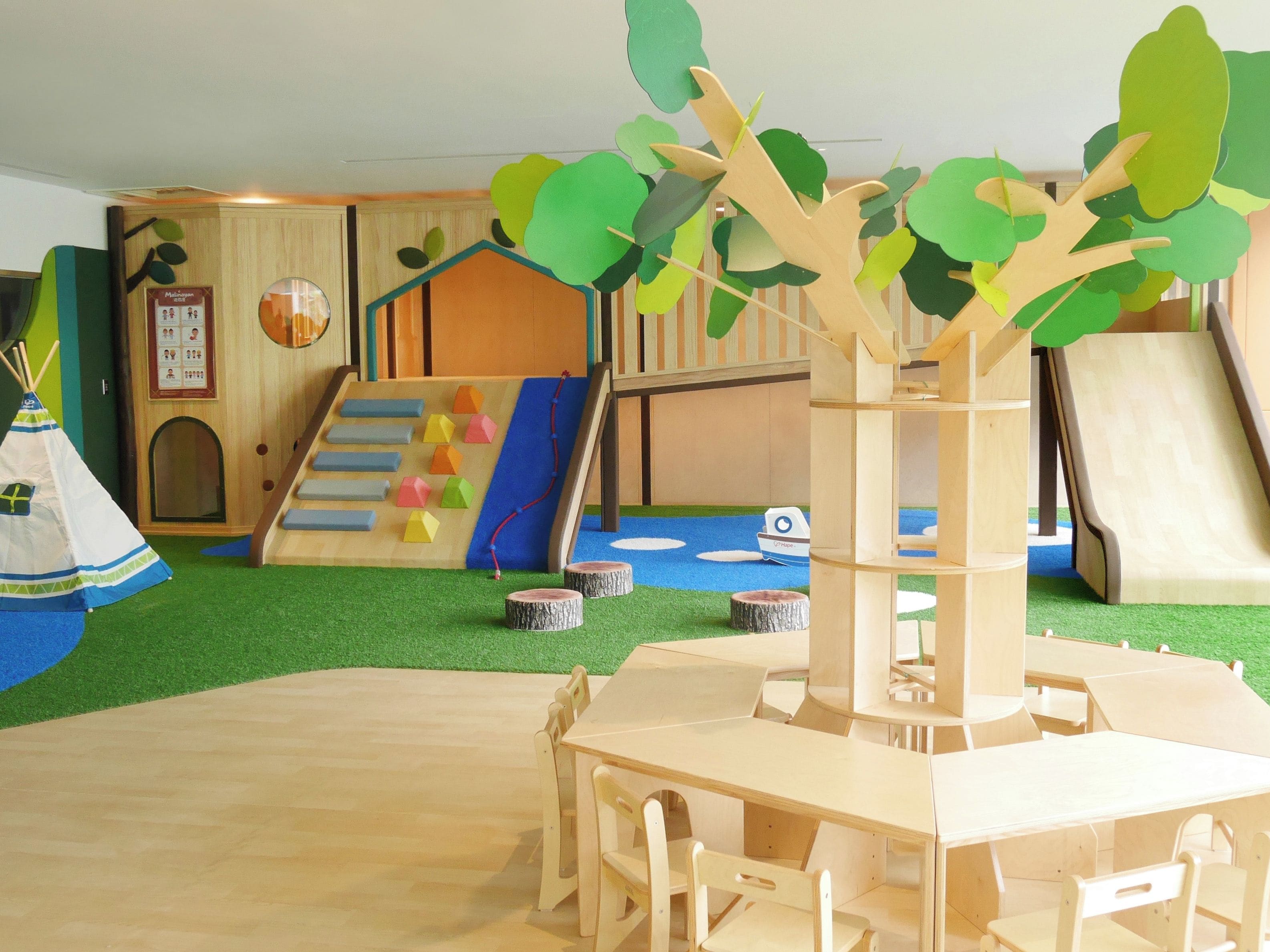 Zona de juegos infantiles con tobogán, pared de escalar y una mesa con sillas.