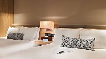 A hotel room with two beds, a nightstand with a lamp, and a wooden headboard.