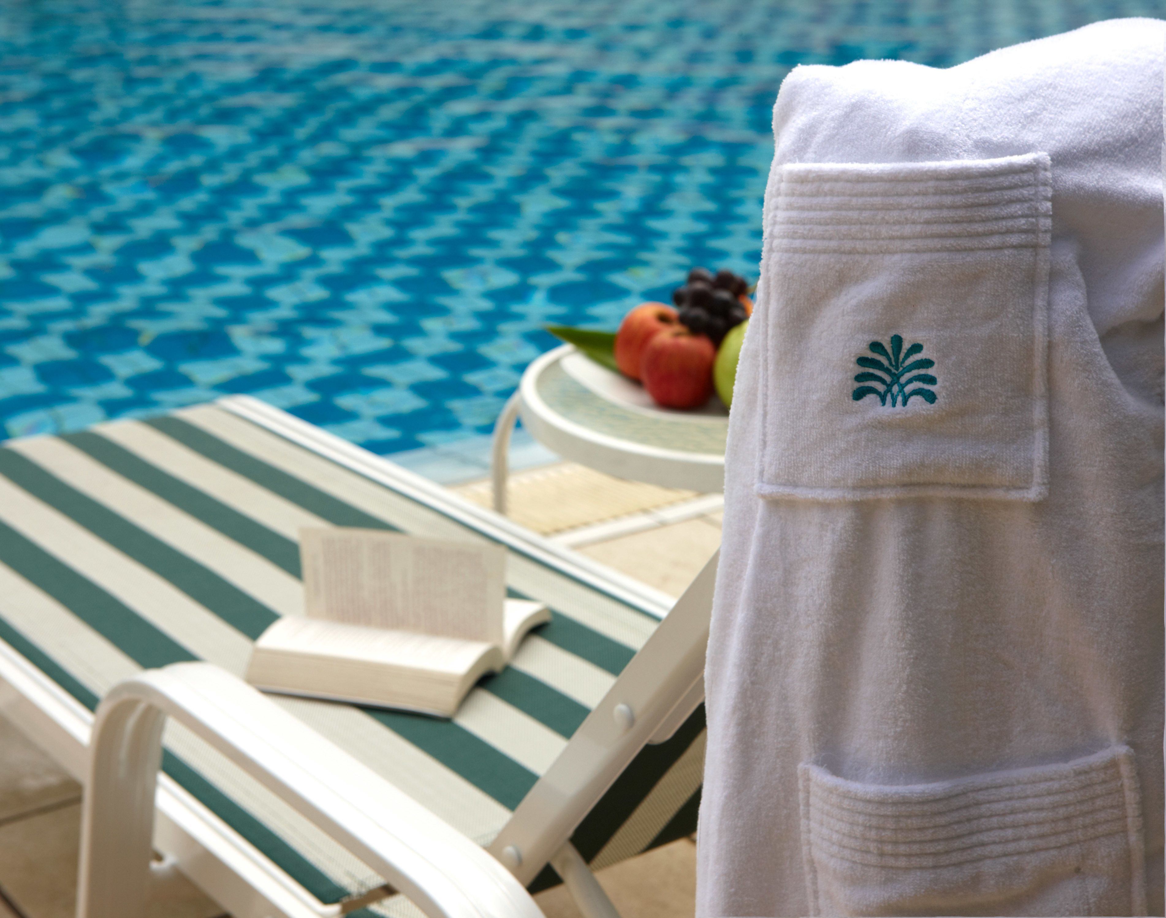 A poolside area with a lounge chair, a towel, and a plate of fruit.