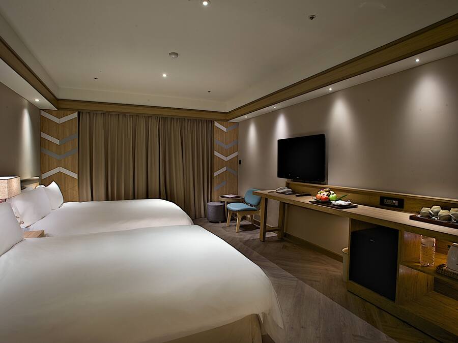 Habitación de hotel con dos camas grandes, un escritorio, un televisor de pantalla plana, una mesita y un minibar.