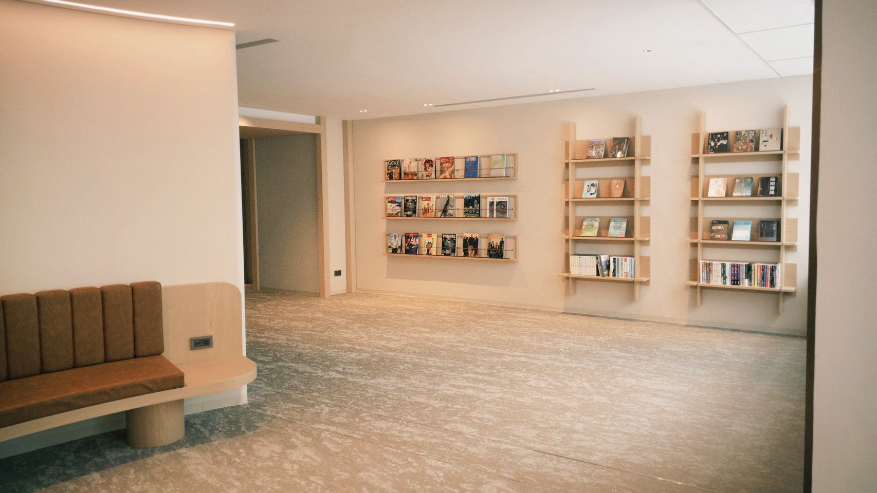 A library with bookshelves, a bench, and a carpeted floor.