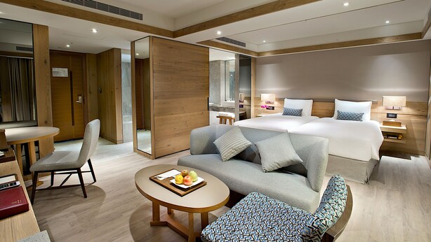 A modern hotel room with a large bed, a sofa, a dining table, and a small kitchen area. - Hotel Royal Chihpen (Taimali)