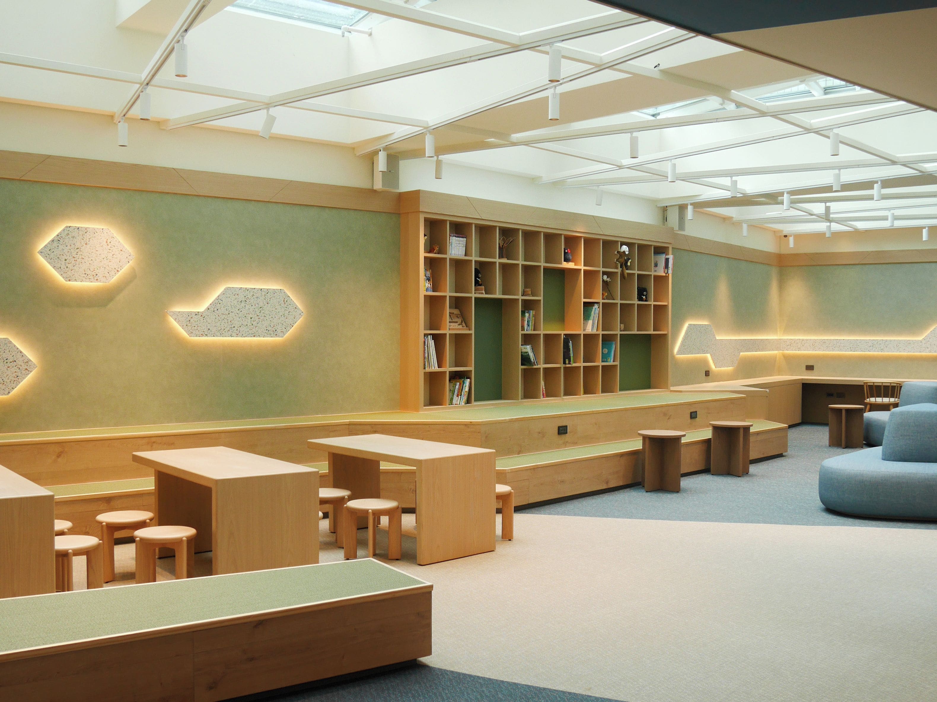 A modern library with wooden furniture, a large bookshelf, and a skylight ceiling.