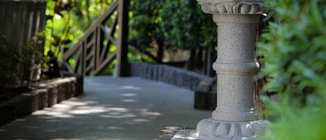 A stone lantern with intricate carvings, a wooden fence, and lush greenery in the background.