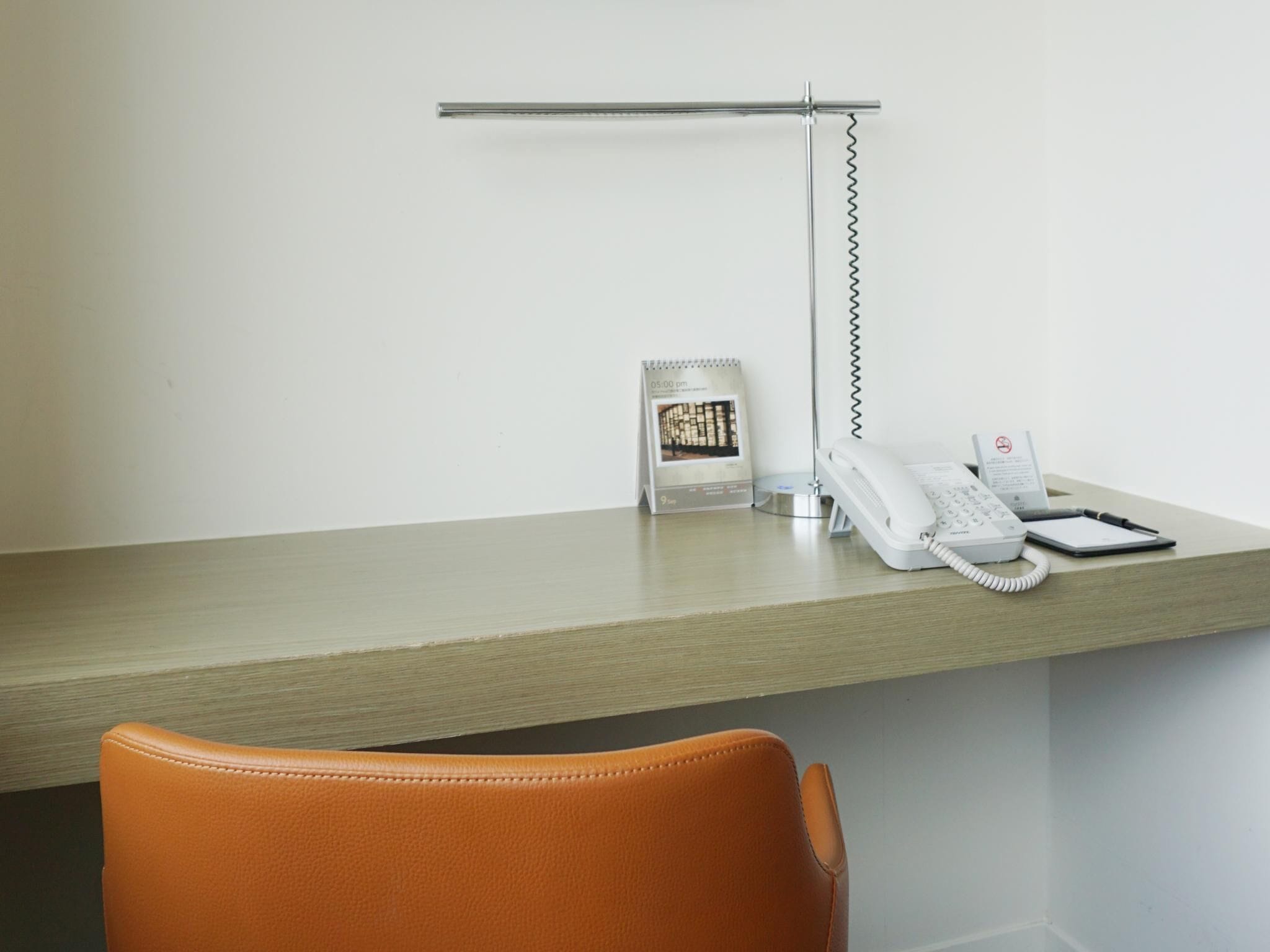 A desk with a telephone, a calendar, and a lamp.