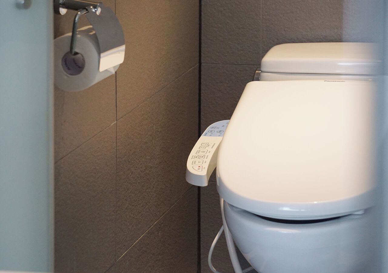 Un inodoro moderno con panel de control y dispensador de papel higiénico.