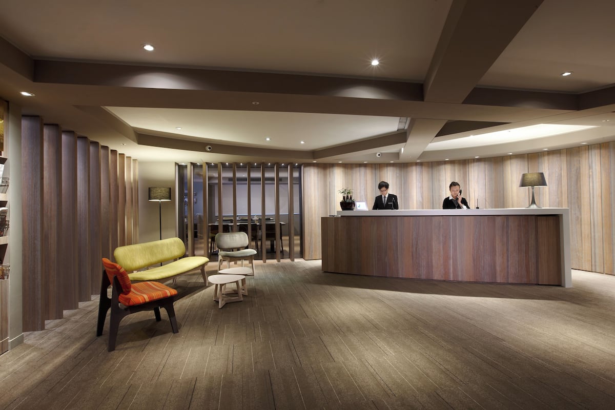 A modern reception area with a reception desk, seating, and a wooden floor.