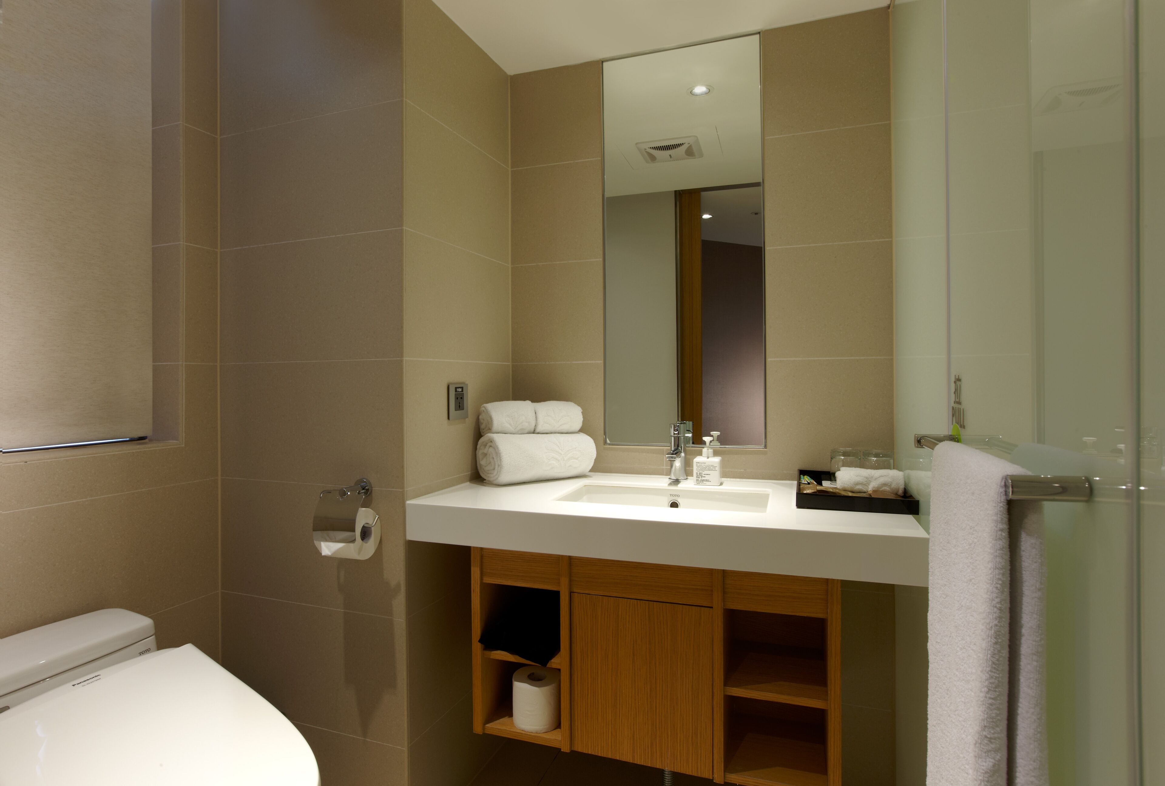 Un baño moderno con lavamanos, espejo y retrete blancos.
