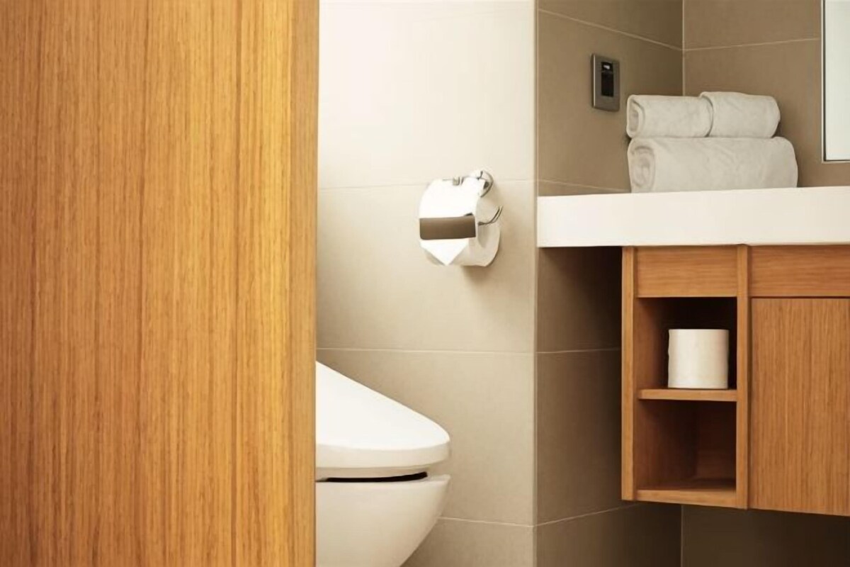 Een badkamer met een toilet, een handdoekrolhouder en een houten kastje met een handdoek.