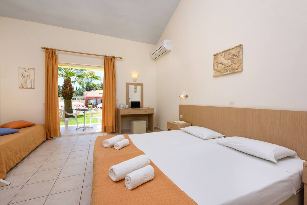 A hotel room with a bed, two bedside tables, a desk, a chair, and a window with curtains.