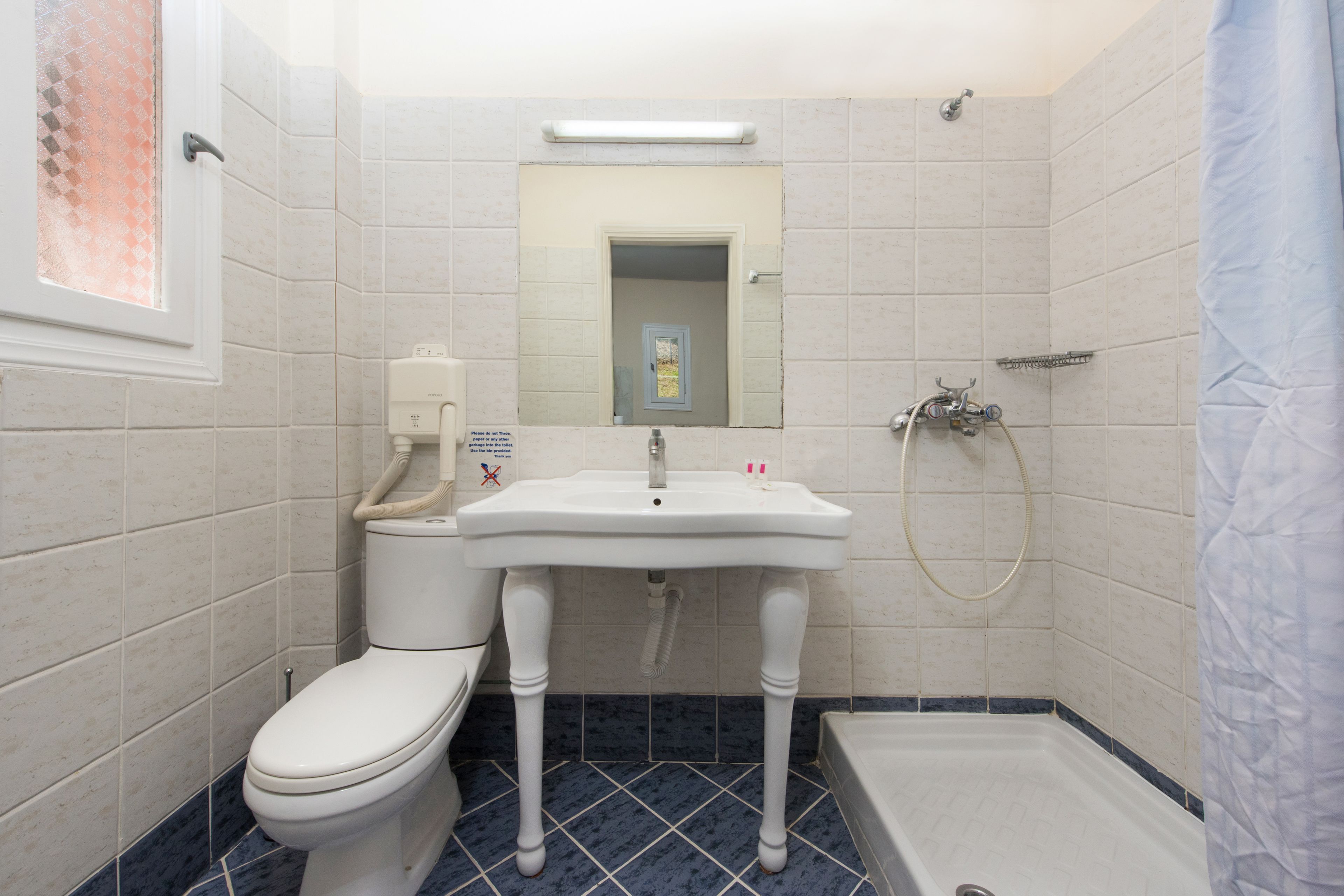 A bathroom with a toilet, sink, and shower.