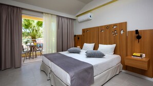 Una habitación de hotel moderna con una cama grande, un cabecero de madera, una mesita de noche con un libro y vistas al exterior.