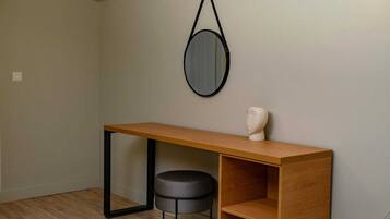A small, modern room with a wooden desk, a round stool, and a bust on the desk.