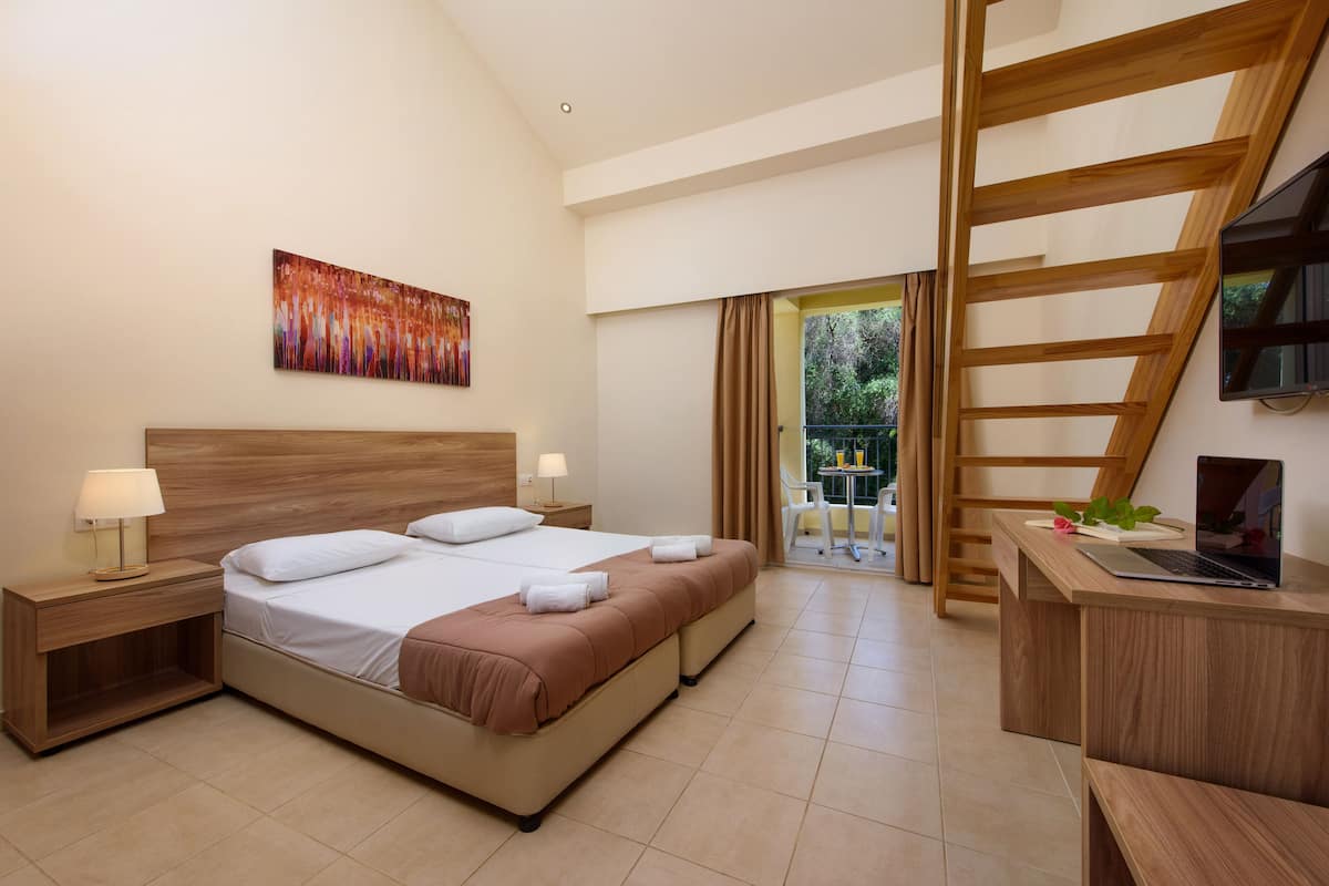A hotel room with a bed, nightstands, a desk with a laptop, a painting on the wall, and a view of the outdoors.