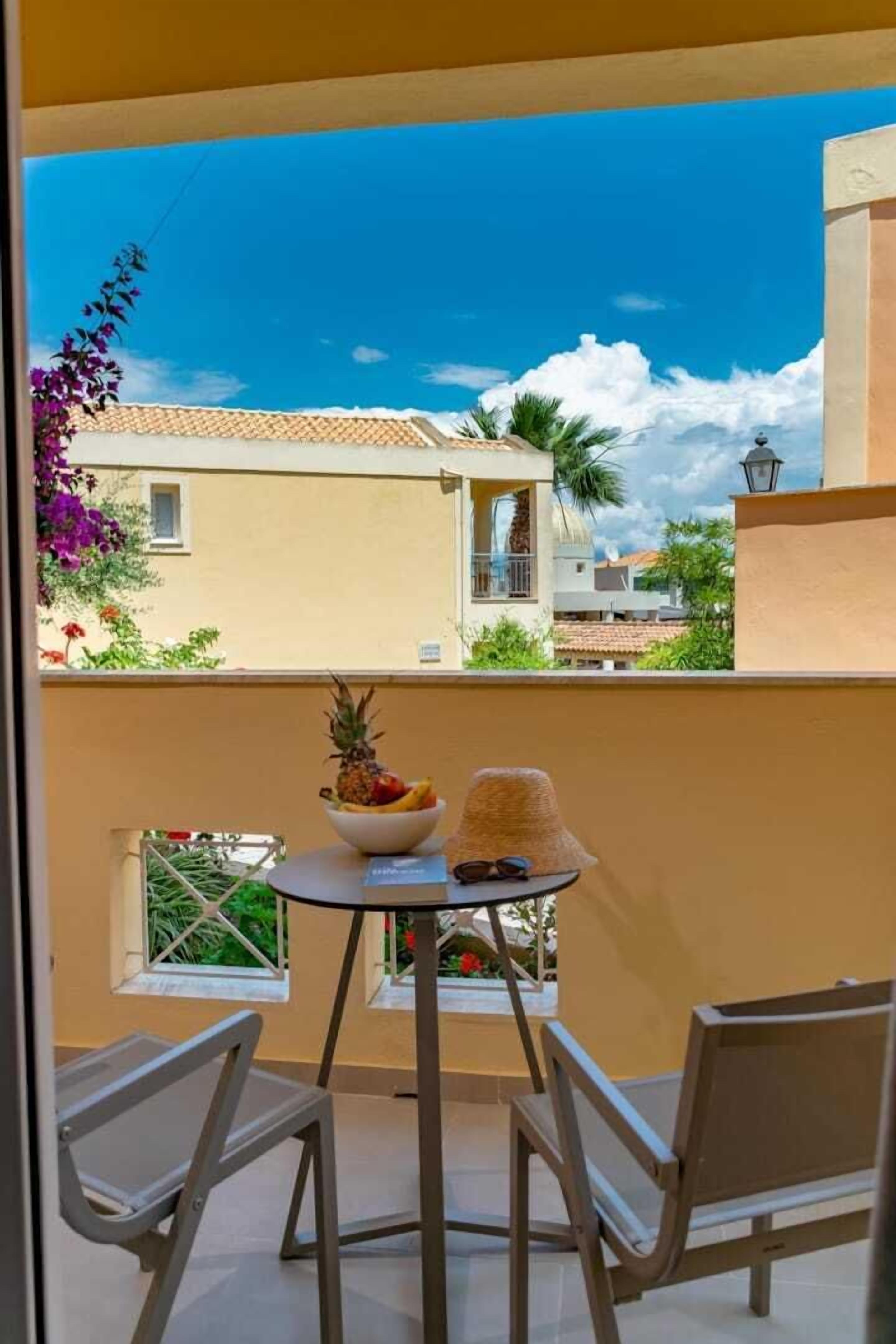 A balcony with a table, chairs, and a bowl of fruit.