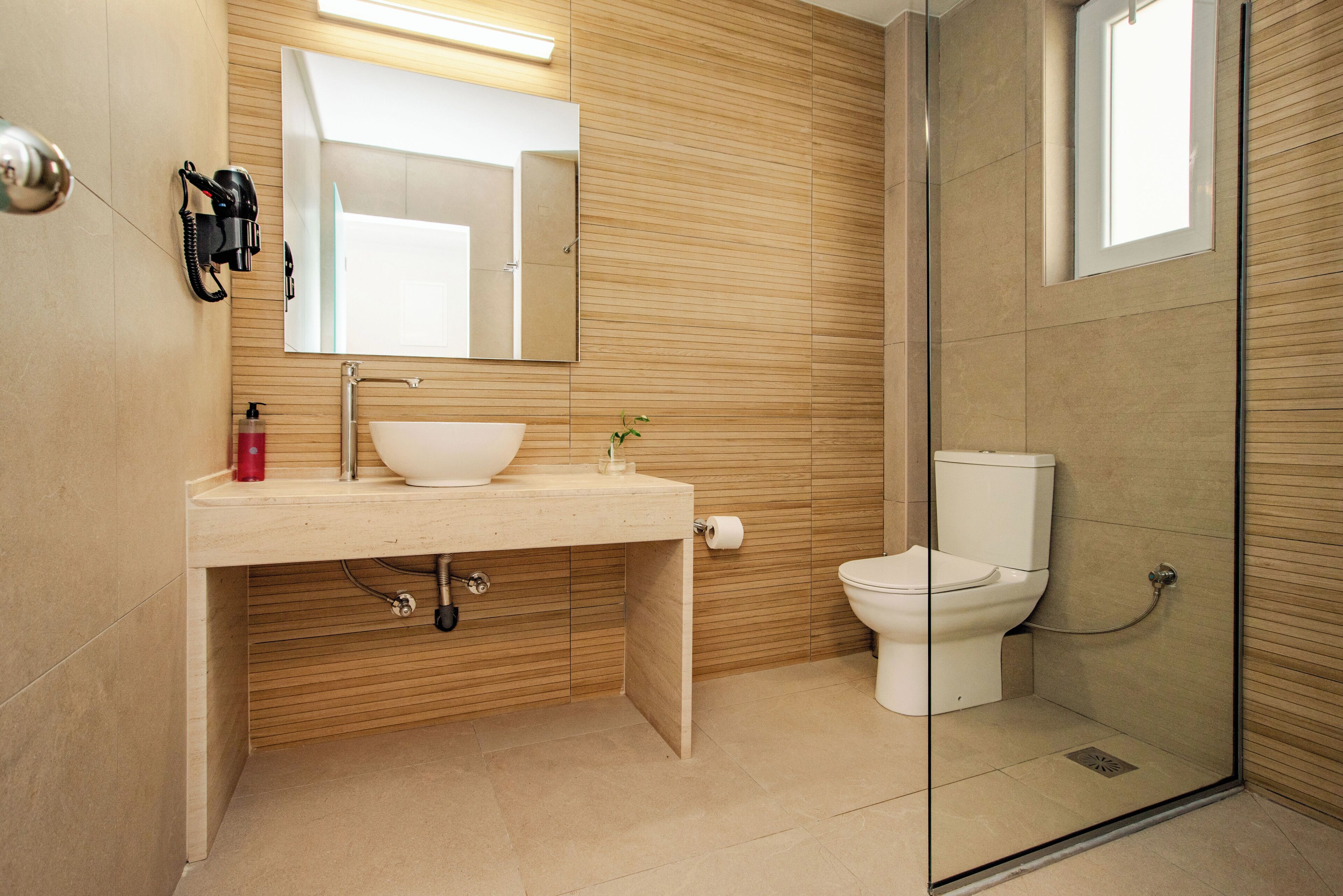 Een moderne badkamer met een wastafel, spiegel, toilet en een douchecabine van glas.