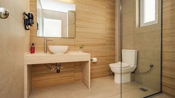 Een moderne badkamer met een wastafel, spiegel, toilet en een douchecabine van glas.