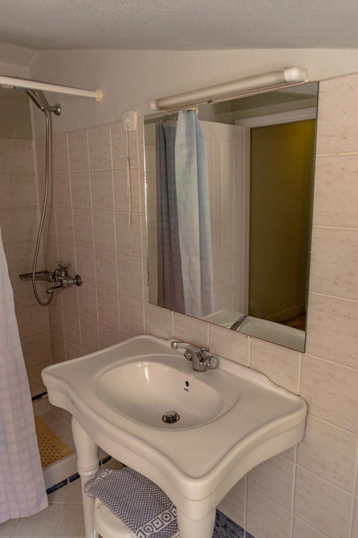 A bathroom with a white sink, a mirror, and a shower area.