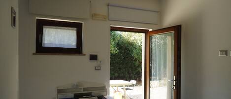 A room with a desk, chair, and a sliding glass door leading to an outdoor area with a table and chairs.