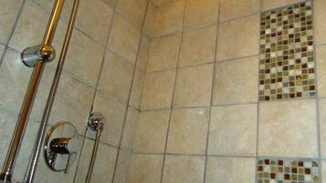A shower with a handheld showerhead and a wall-mounted faucet.