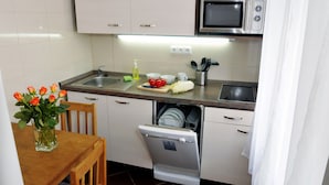 A compact kitchen with a dishwasher, microwave, and a dining area with a table and chairs. - Apartment Prague City (Prague)
