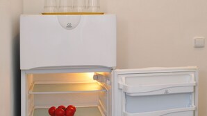 An open refrigerator with shelves containing tomatoes and a head of lettuce. - Apartment Prague City (Prague)