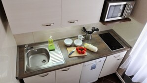 A compact kitchen with a sink, a microwave, and a dishwasher. - Apartment Prague City (Prague)