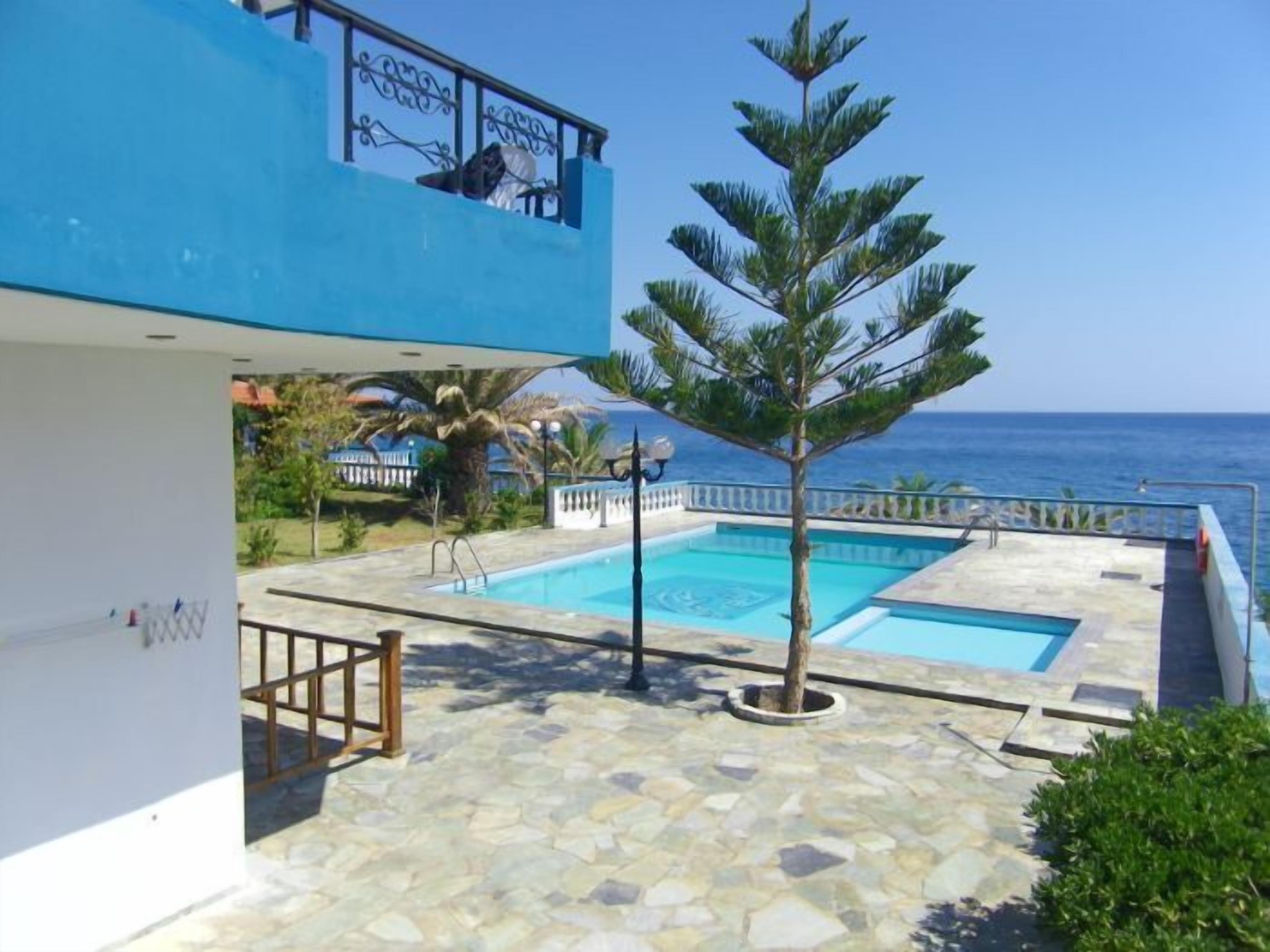 A two-story building with a pool area, including two swimming pools and a small tree.