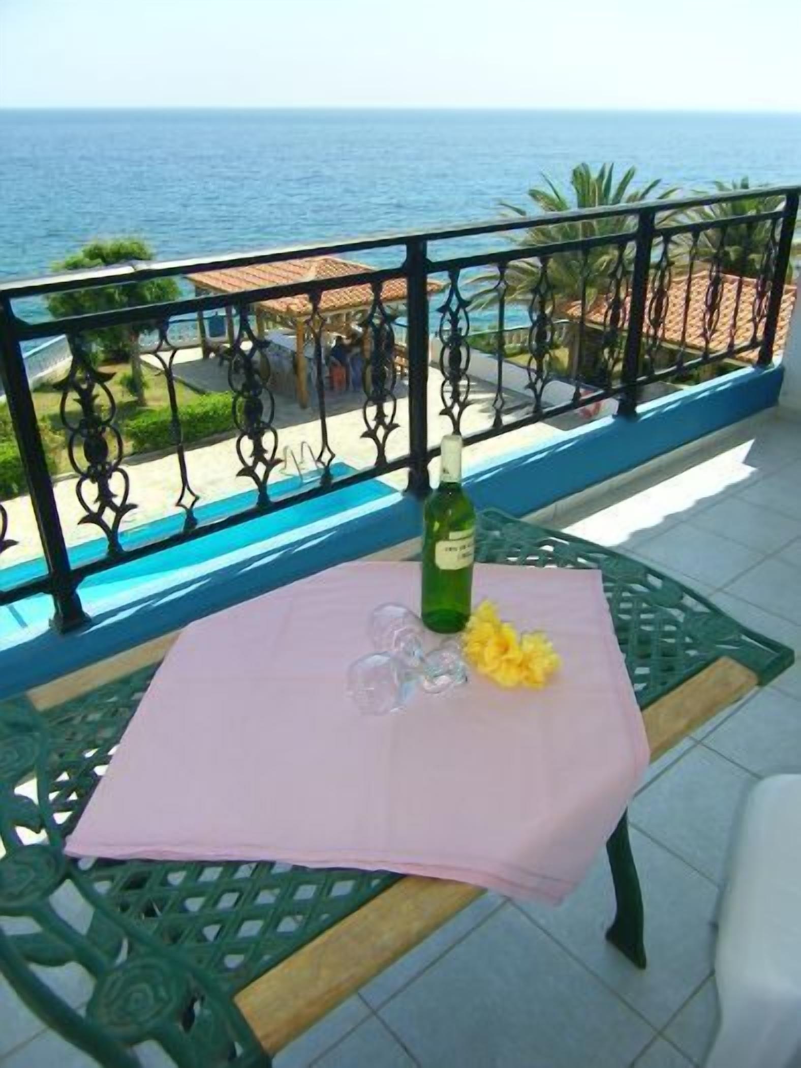Un balcon avec une table dressée pour deux personnes, agrémentée d’une bouteille et de verres, offrant une vue sur la côte.