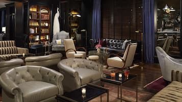 A luxurious lounge with leather sofas, a bar area, and a bookshelf filled with books.