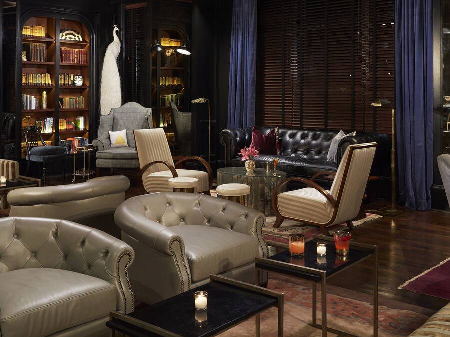 Un salon luxueux avec des canapés en cuir, un coin bar et une bibliothèque remplie de livres.