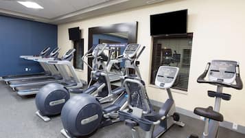 Une salle de sport équipée de tapis de course, d’appareils elliptiques et de vélos d’appartement.