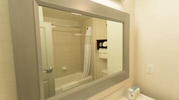 A bathroom with a bathtub, a shower curtain, a toilet, and a mirror.