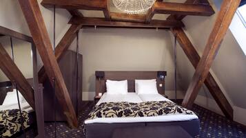 A bedroom with a wooden ceiling and a bed with white and patterned bedding.