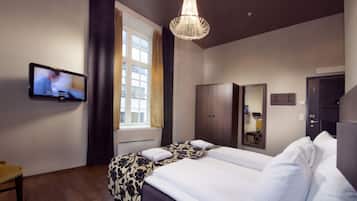 Een hotelkamer met een bed, een televisie, een kast en een spiegel.