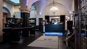 A hotel lobby with a reception desk, seating area, and a chandelier. - Banken Hotel (Haugesund)