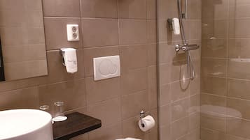 Een moderne badkamer met toilet, wastafel en douche met glazen wand.