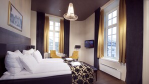 A hotel room with a large bed, a television, a chair, and a window with curtains. - Banken Hotel (Haugesund)