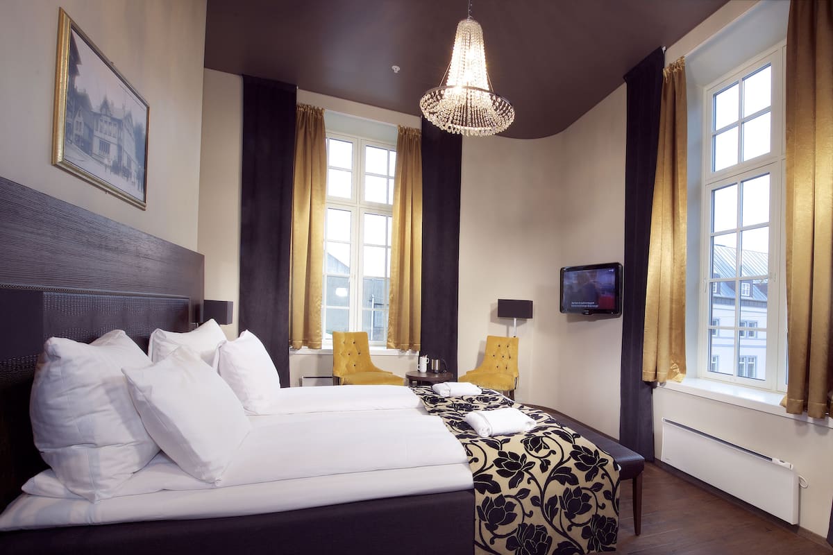 A hotel room with a large bed, a television, a chair, and a window with curtains.