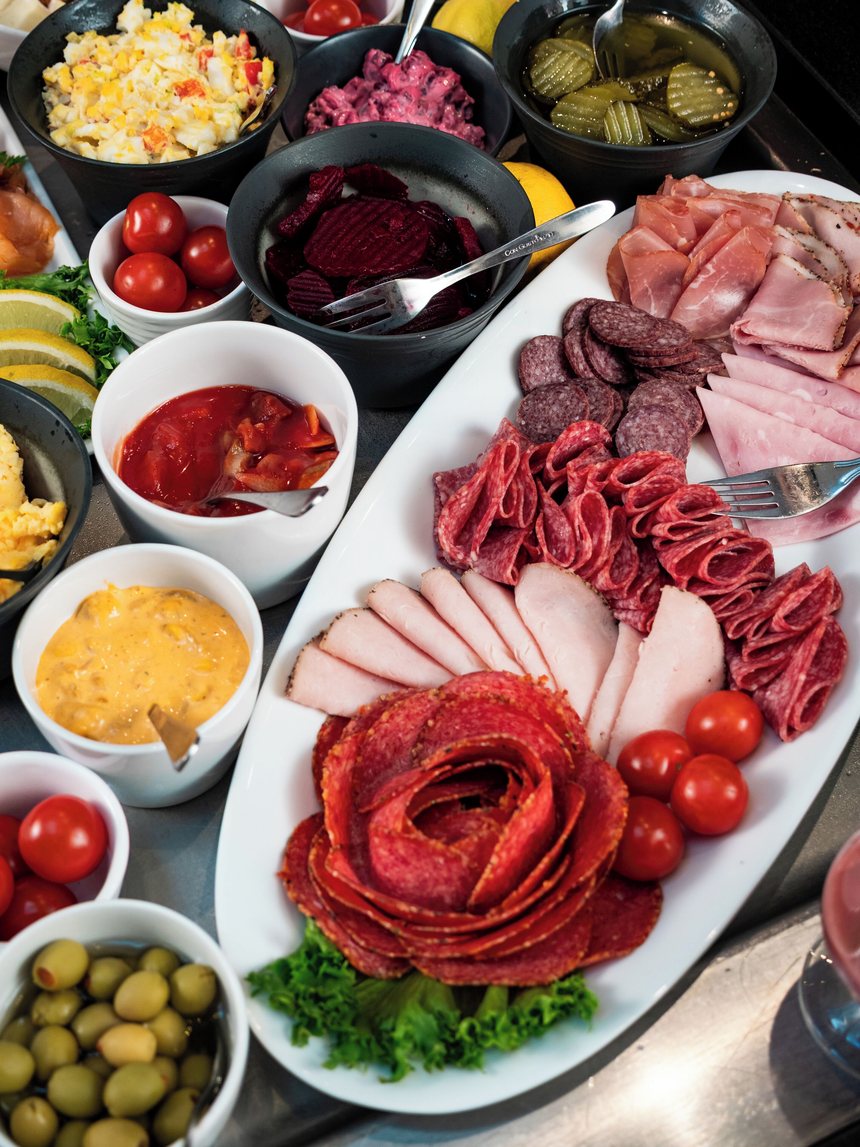 A variety of food items including sliced meats, olives, and condiments arranged on a table.