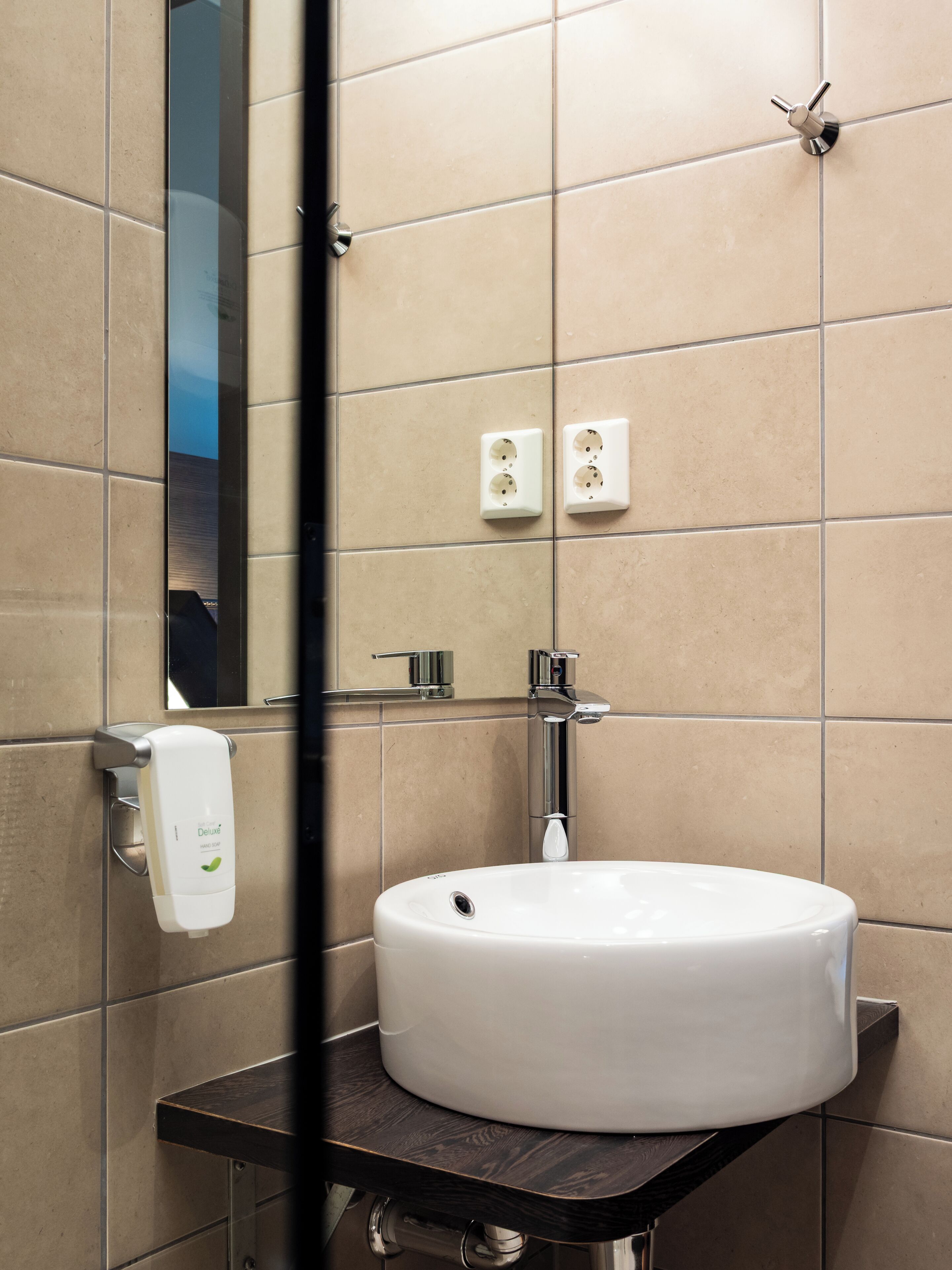 Un baño moderno con un lavabo redondo, un espejo y un dispensador de jabón.