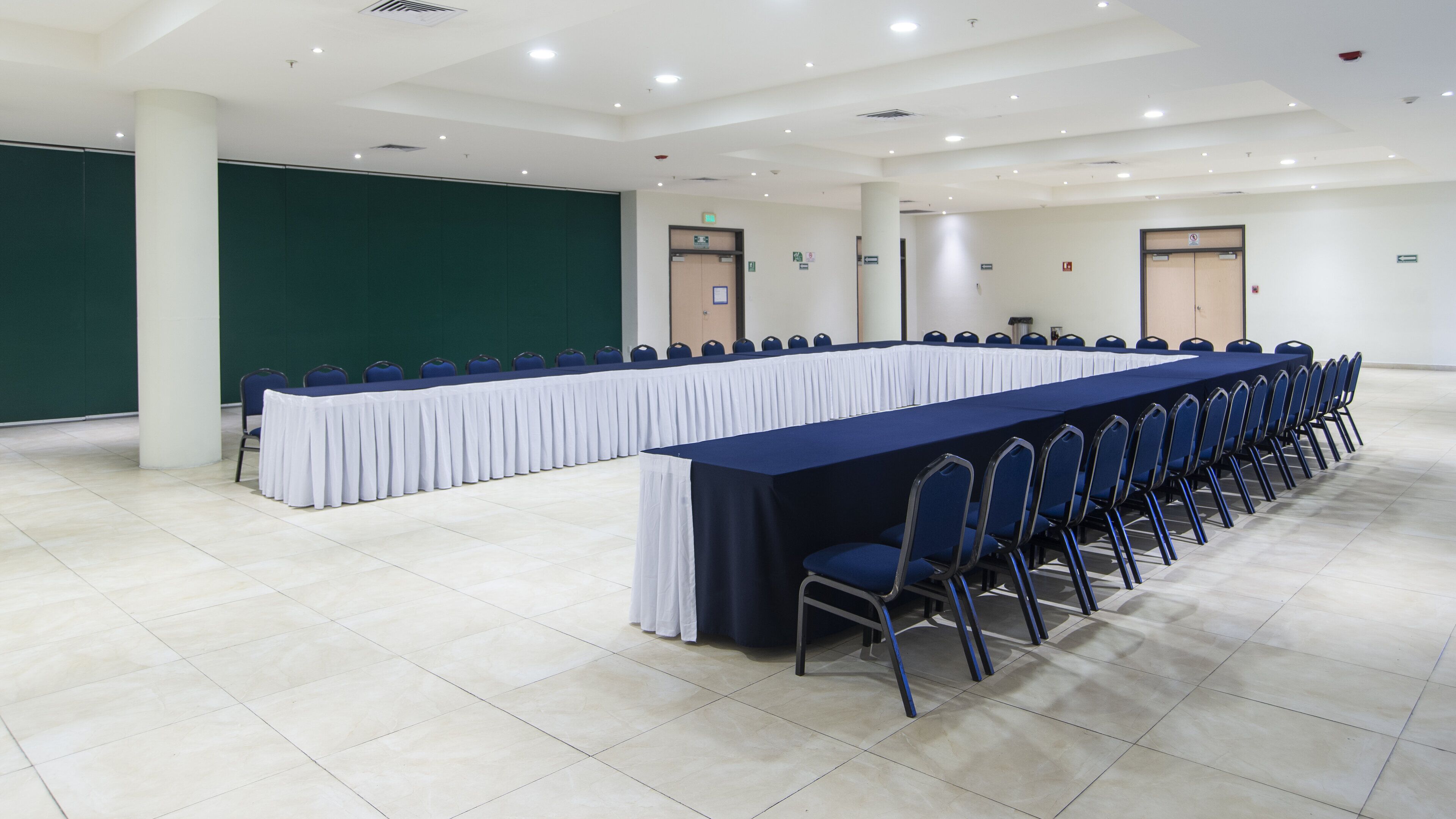 A conference room with a long table, chairs, and a projection screen.