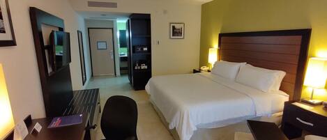 Una habitación de hotel con cama, escritorio, silla y televisor.