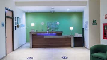 A reception desk with a green wall, framed certificates, and a blue-lit counter.